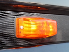 Kompaktlampe K�hlergrill Doubledutch mit leuchtendem orangefarbenem Glas, montiert auf dunklem LKW-K�hlergrill.