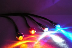 Mehrere schraubbare LED-Leuchtmittel mit Metallgeh�use in Orange, Rot, Wei� und Blau leuchten auf dunklem Untergrund.