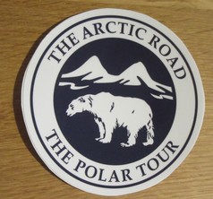 Blau-wei�er runder Aufkleber mit einem Polarbaer, Bergen und dem Schriftzug "The Arctic Road The Polar Tour".