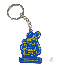 Schl�sselanh�nger LKW Zubeh�r: Blauer Anh�nger mit gelbem Trucker-Motiv, Text "Am alten Autohof Berg" und "www.LKW-ZUBEHOER.de".