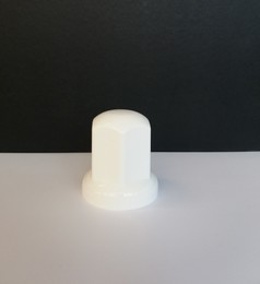 Wei�e, lange Radmutterkappe aus Kunststoff auf hellem Untergrund.