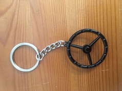 Schl�sselanh�nger mit schwarzem Old School Lenkrad und silbernem Schl�sselring auf Holz.