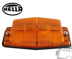 Orange Hella Zusatzblinklicht mit gerippter Kunststofflinse, schwarzer Basis und sichtbaren Befestigungsschrauben.