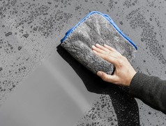 Hand trocknet dunklen Autolack mit grauem, blau umrandeten MEGA Flausch Plus+ Trocknungstuch.