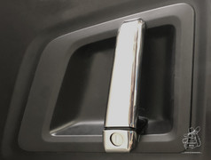 Gl�nzende, gepresste Edelstahl T�rgriff Applikation auf einer dunklen LKW-T�r.