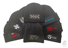 Mehrere schwarze Winterm�tzen mit verschiedenen Stickereien im Patchfeld, darunter "Old Skool" und "BESSER".