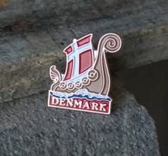 Metall-Pin in Form eines Wikingerschiffs mit rot-wei�em Segel und blauen Wellen. Schriftzug DENMARK.