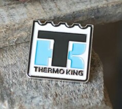 Scandi Pin Thermo King Anstecker. Wei�er Pin mit gezacktem Rand, schwarzen und hellblauen TK-Buchstaben und THERMO KING Schriftzug.
