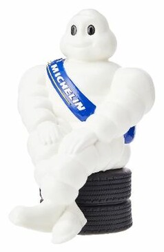 Wei�es Original Michelin M�nnchen sitzt auf schwarzen Reifen, mit blauer MICHELIN Sch�rpe.