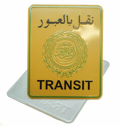 Ein golden-gelbes Transit-Schild mit arabischer Schrift und Emblem. Ein weiteres, helles Schild liegt darunter.