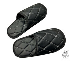 Ein Paar schwarze Kunstleder-Pantoffeln mit hellgrauen Steppn�hten.