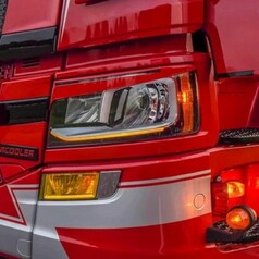 Nahaufnahme des roten Scania NG Lastwagens mit leuchtenden Angel Eyes und Blinklicht.