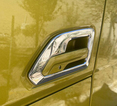 Gl�nzender Edelstahl-T�rgriffrahmen auf einer gelb-gr�nen LKW-T�r.